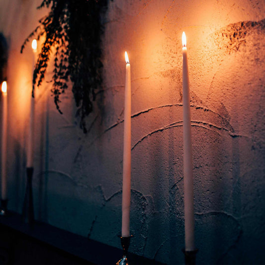 Handcrafted beeswax taper candles neatly arranged on a retail shop shelf, showcasing their natural golden hue and inviting texture