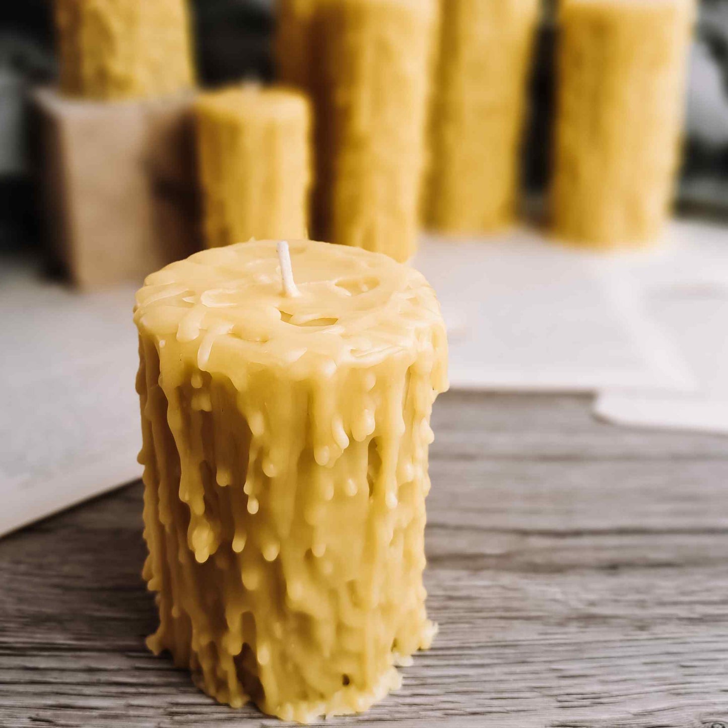 Artisan-crafted beeswax candles with a bespoke drip effect, displayed against a dark background, highlighting their unique shapes and sizes