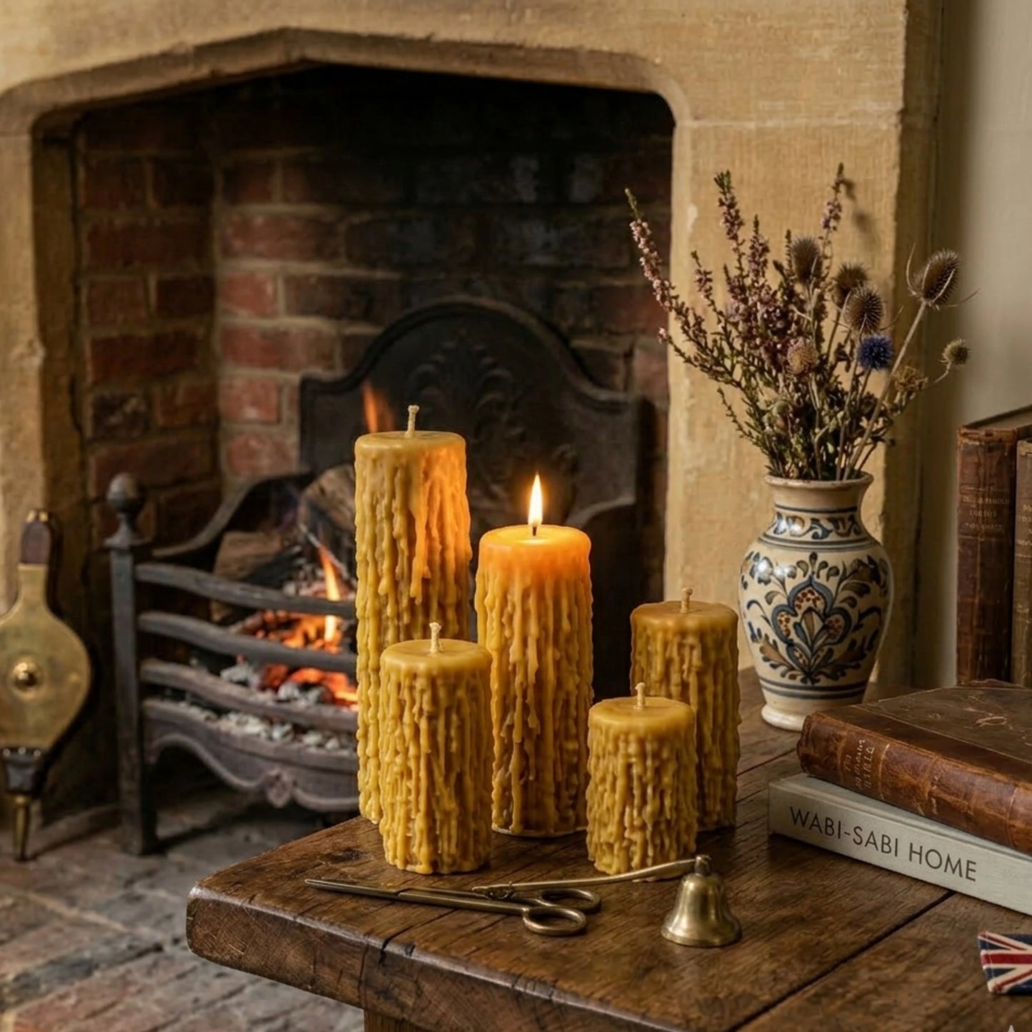 A set of four graduating-height beeswax pillar candles with a deep drip texture. One is clearly lit in the front. The candles are displayed on pages from an old book, showing their detailed, golden-yellow texture against a dark fabric background.