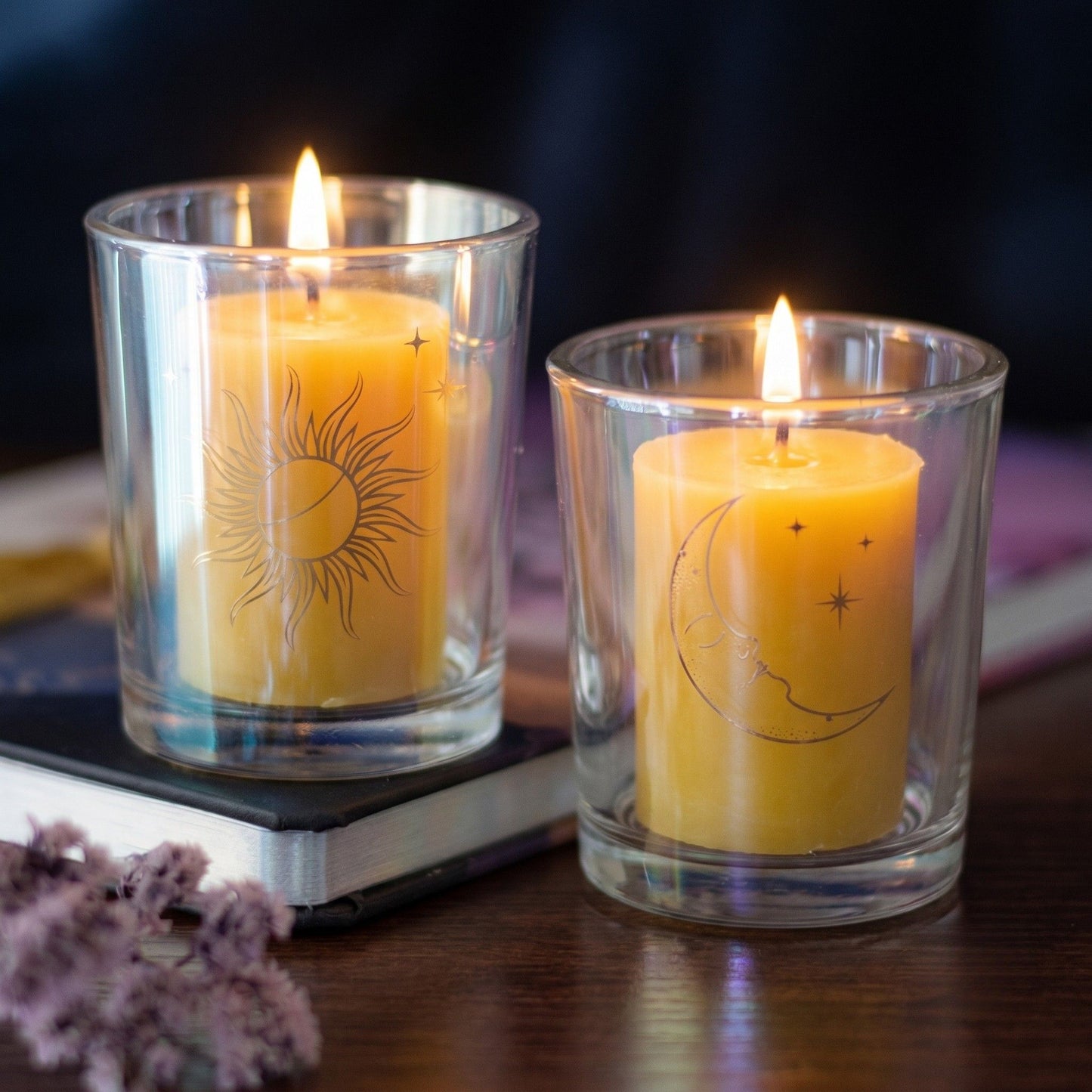 Front view of two clear iridescent glass celestial candle holders featuring gold foil sun and moon designs on a pure white background.